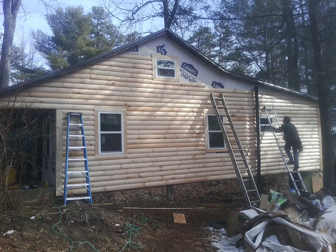 Ladders set against fresh log siding during an exterior remodel in Almond