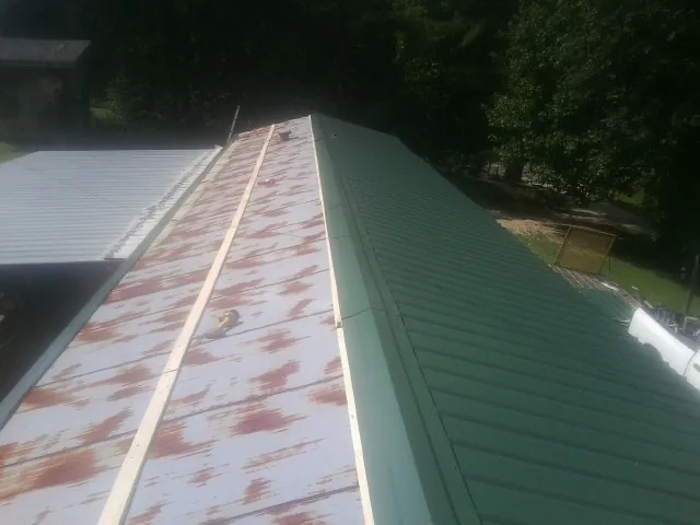 Old rusted panels beside newly installed green metal roofing — Wind Damage Roof Repair by Roofing Brothers in Almond