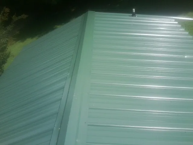 New green metal panels meeting at the ridge of a roof — Flat Roof Repair work by our crew in Almond
