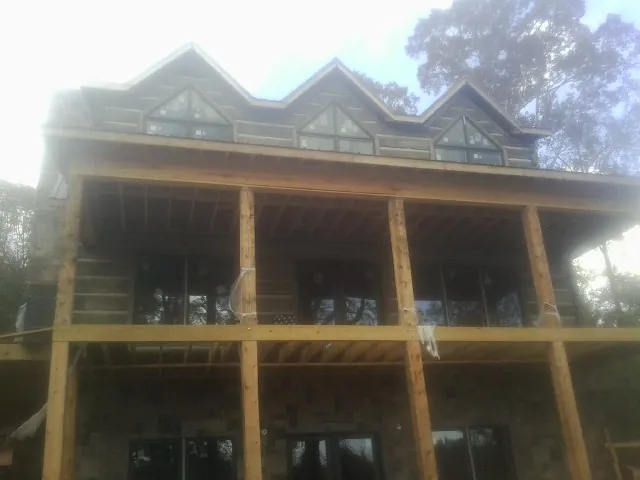 Dormers and porch framing on a large log home under construction — Roof Coating work by our crew in Almond