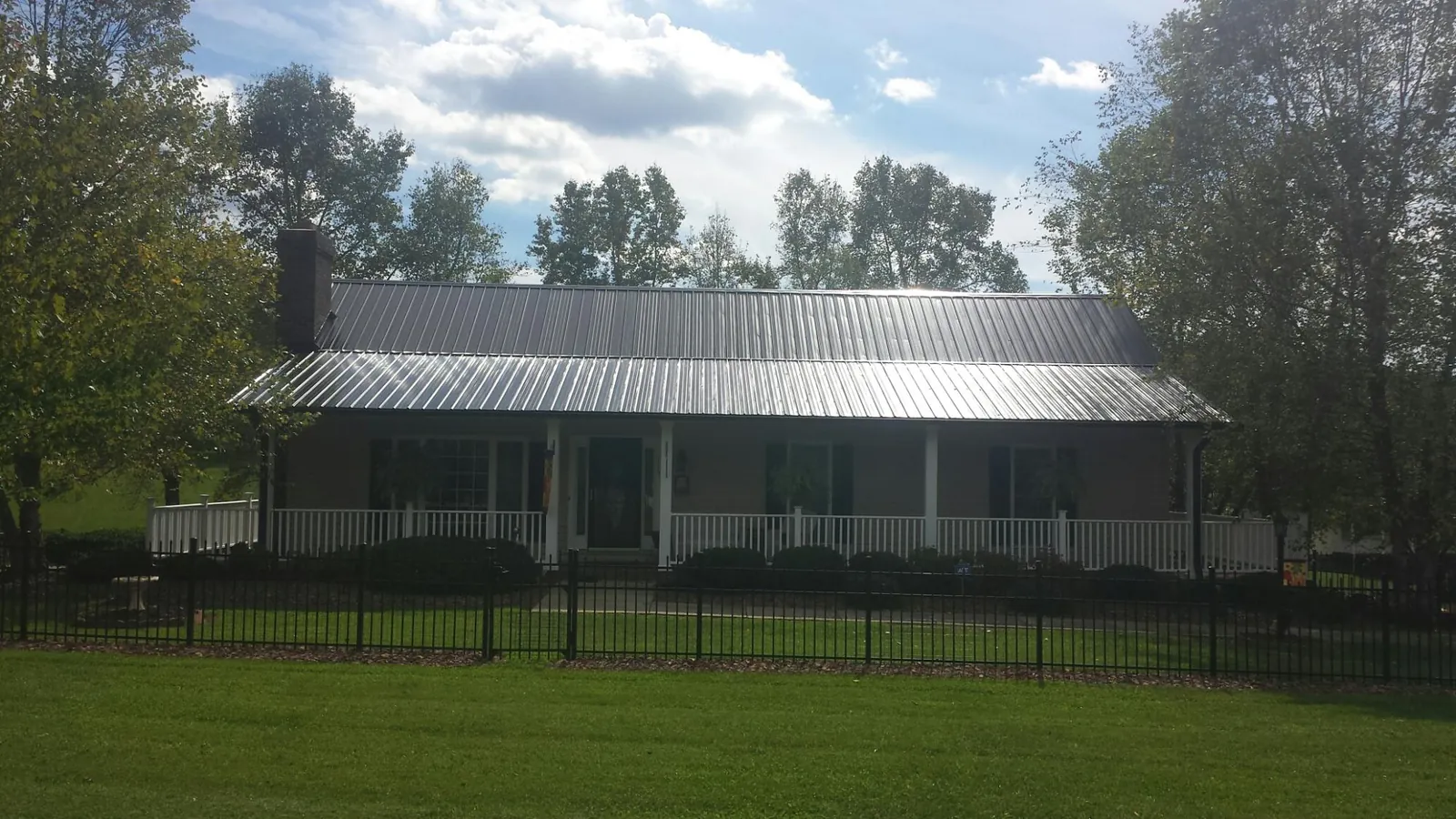 Gray metal roof on a brick ranch with a full width front porch — Gutter Guard Installation work by our crew in Almond